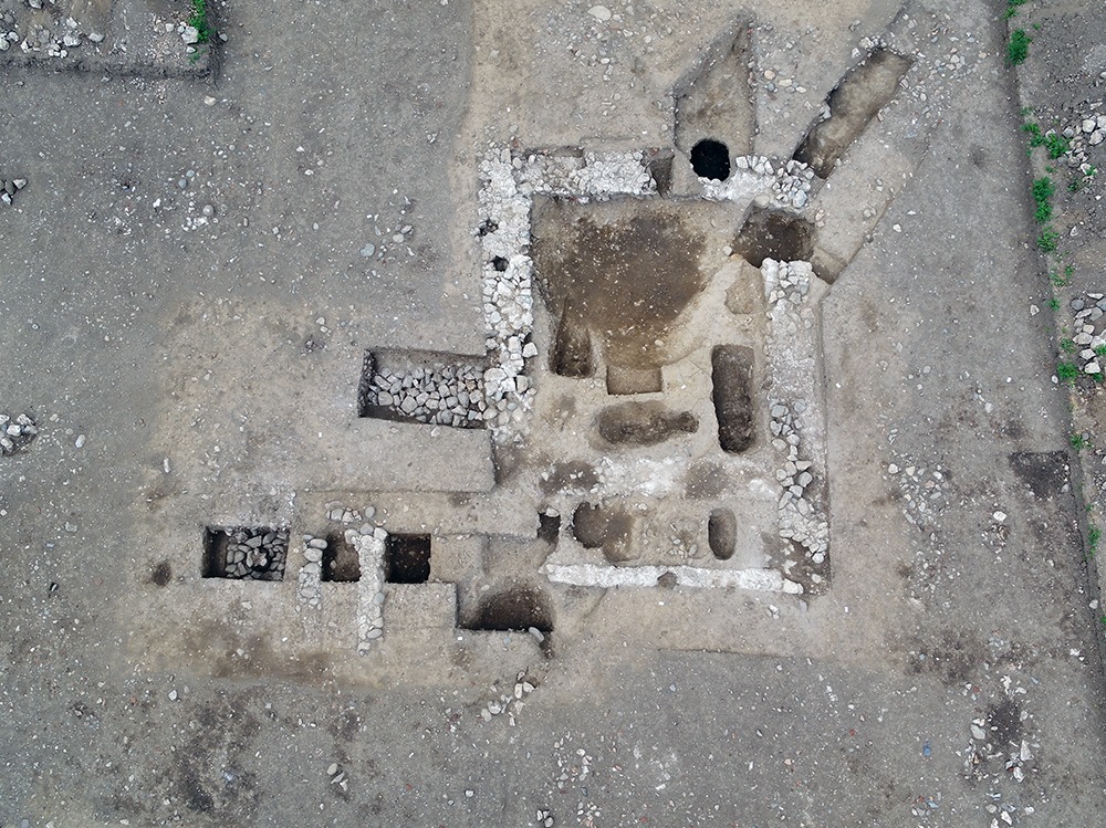 Cette image représente une vue aérienne d'un chantier de fouilles archéologiques, avec visualisation des fondations et d'anciennes sépultures
